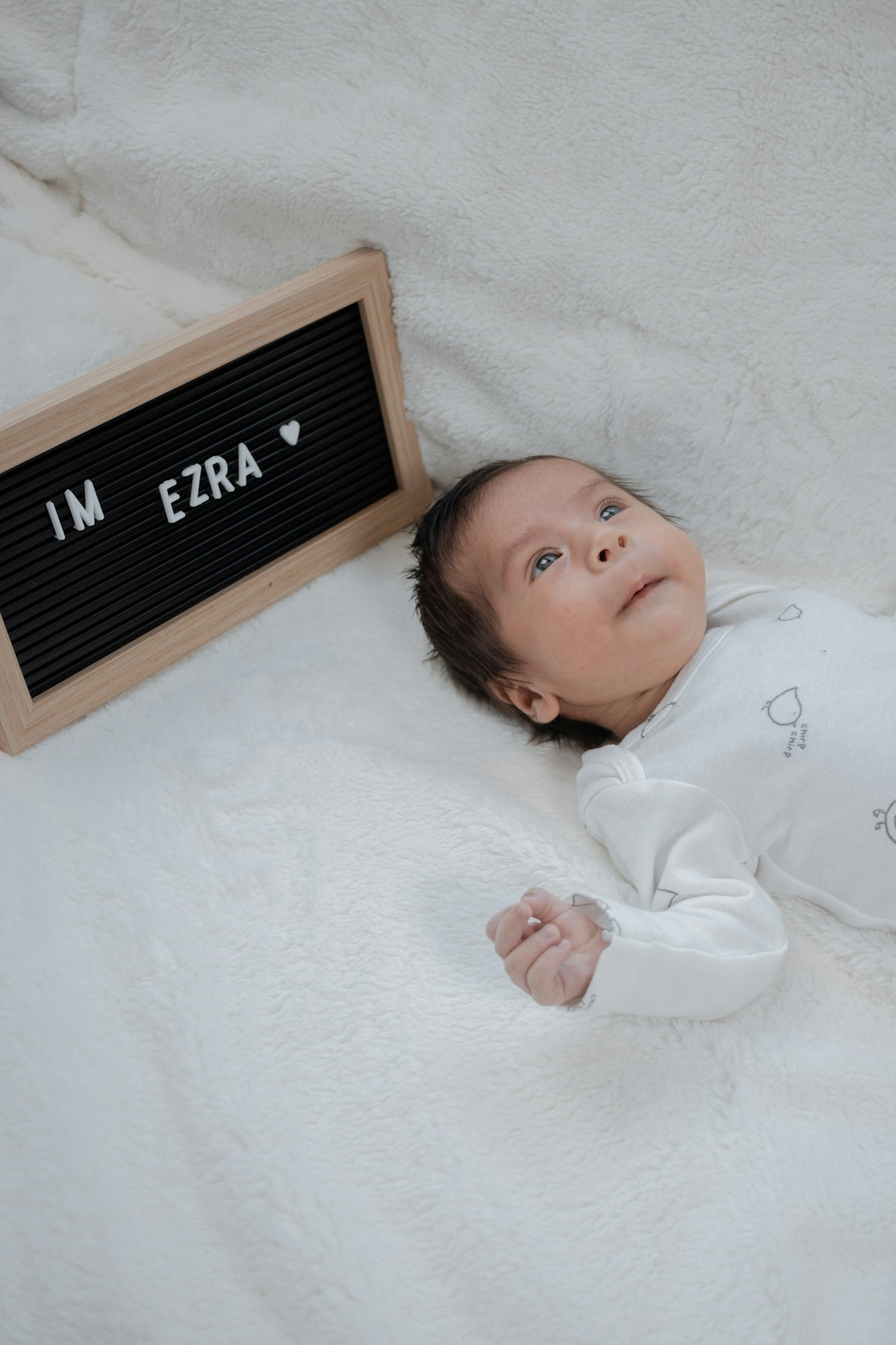 a baby laying on a blanket next to a sign