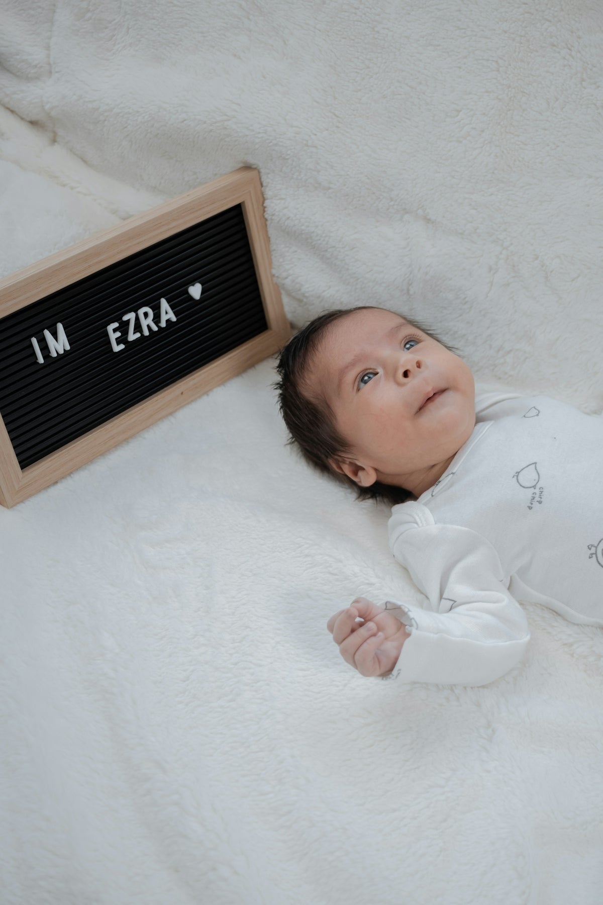 a baby laying on a blanket next to a sign